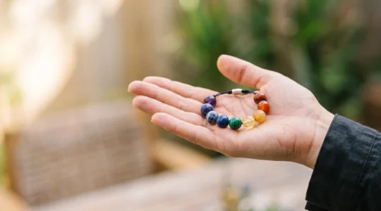 Bracelet en pierres naturelles multicolores posé sur une main ouverte, symbolisant l'équilibre énergétique des sept chakras