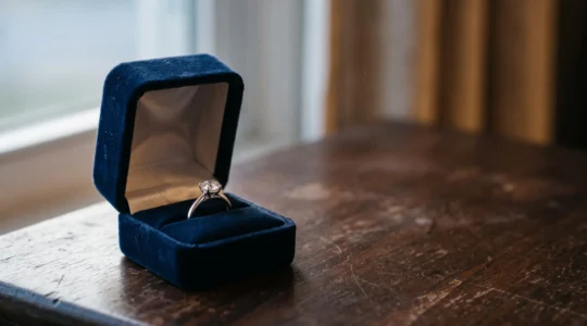 Une bague de fiançailles solitaire posée délicatement dans un écrin ouvert, entre lumière tamisée et discrétion, juste avant la demande en mariage